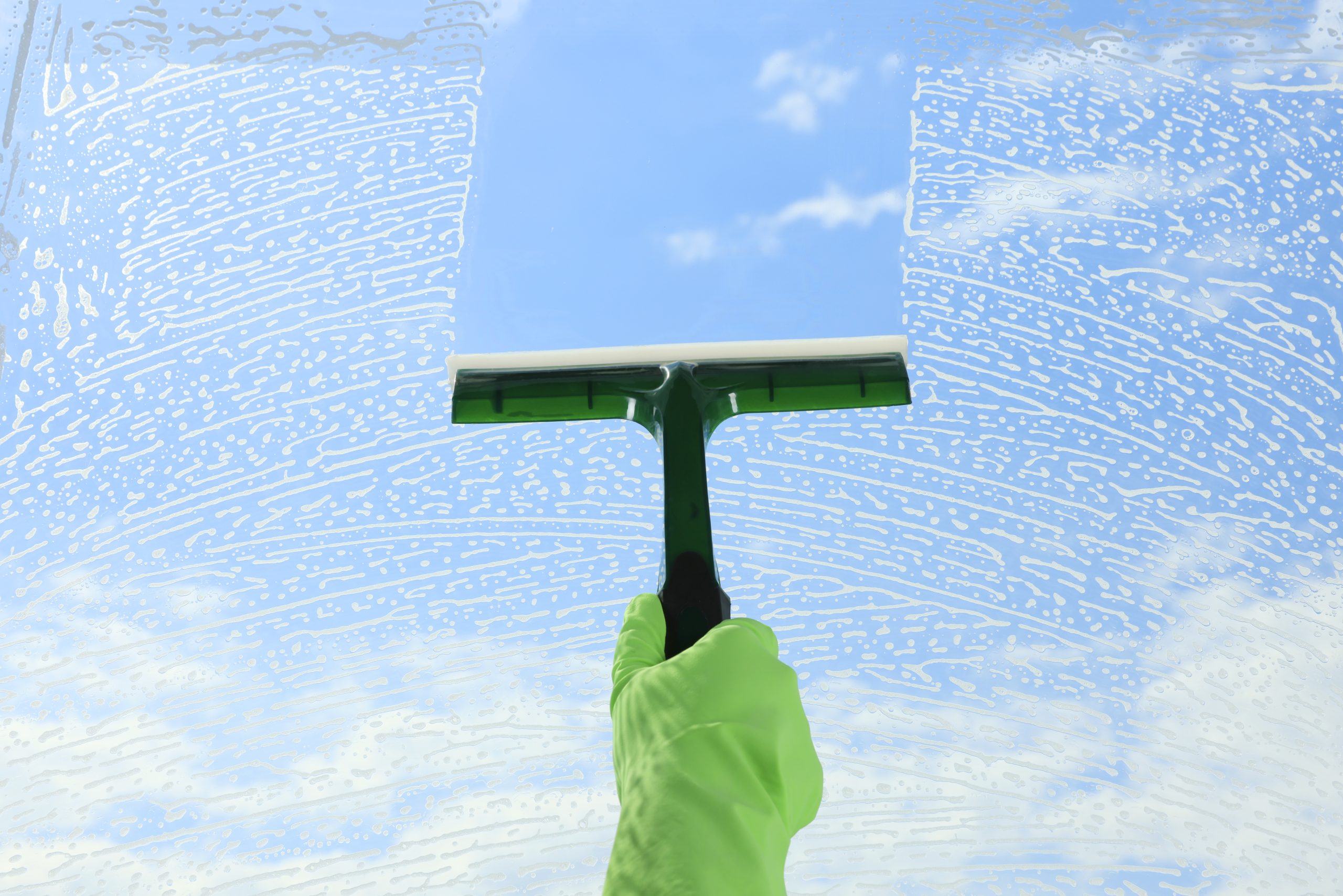 Fensterreinigung mit Abzieher vor blauem Himmel